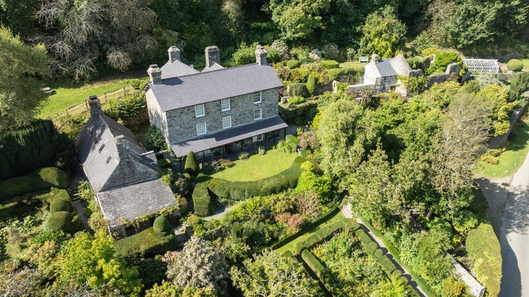 Aerial view of a stone-built country house with green gardens.